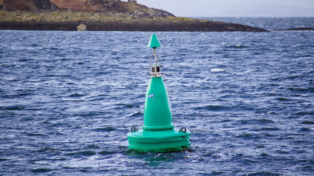 a small green buoy in the water - navigational aid